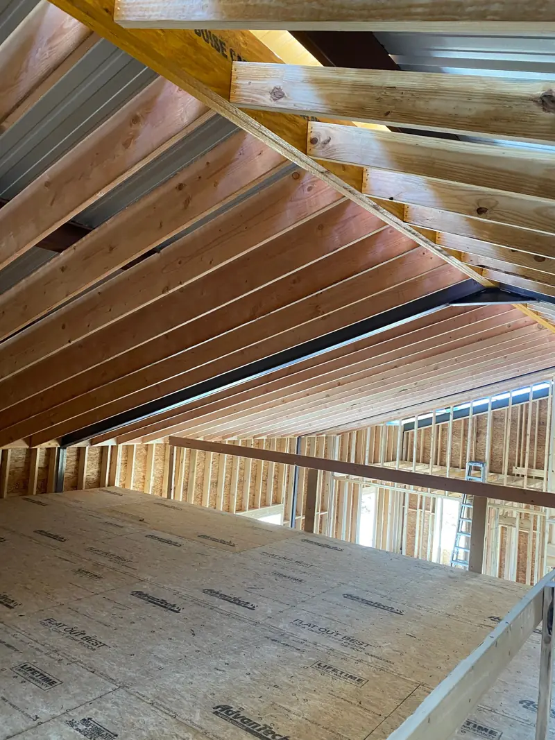 Loft with wood rafters overhead and the subfloor down.