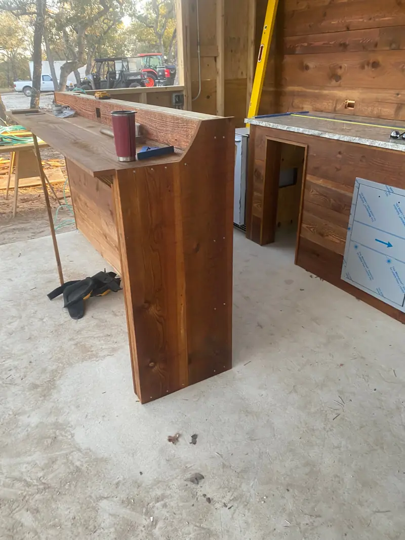 Rustic cedar bar with a matching cedar cabinet on a concrete patio.