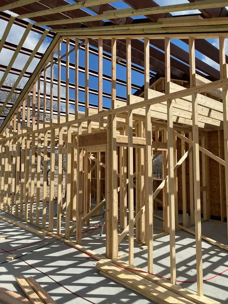 Wood wall framing on a slab under a steel roof frame.