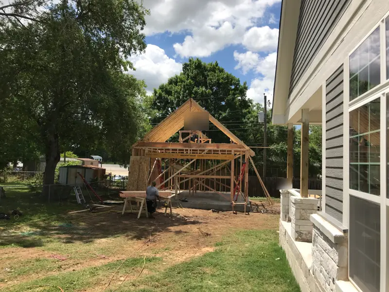 Rafters going up on a new detached garage, seen from the porch of the house.