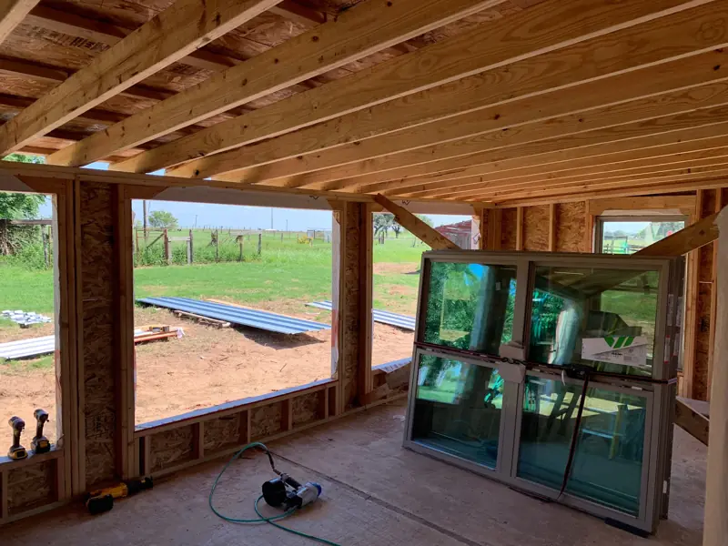 Ceiling joists and window openings framed, new windows waiting on the floor.