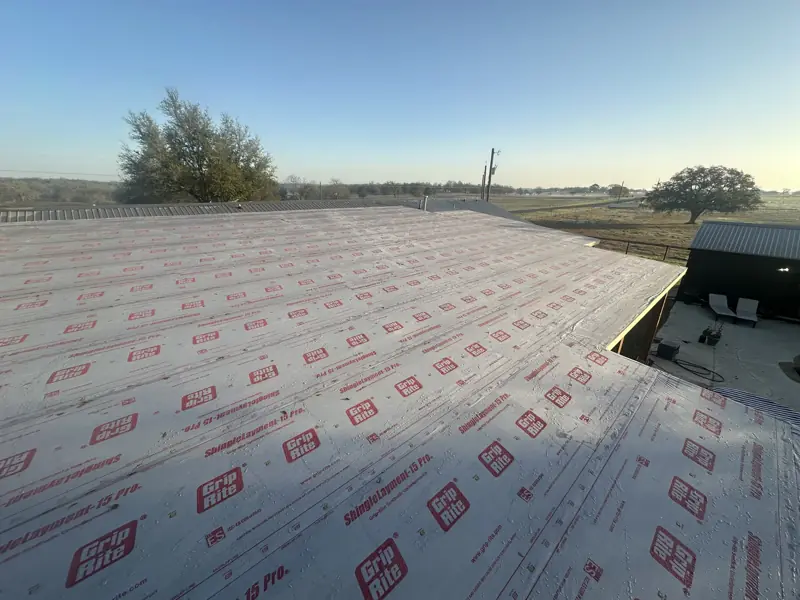 Synthetic roof underlayment covering the new patio roof deck, with pasture and trees beyond.