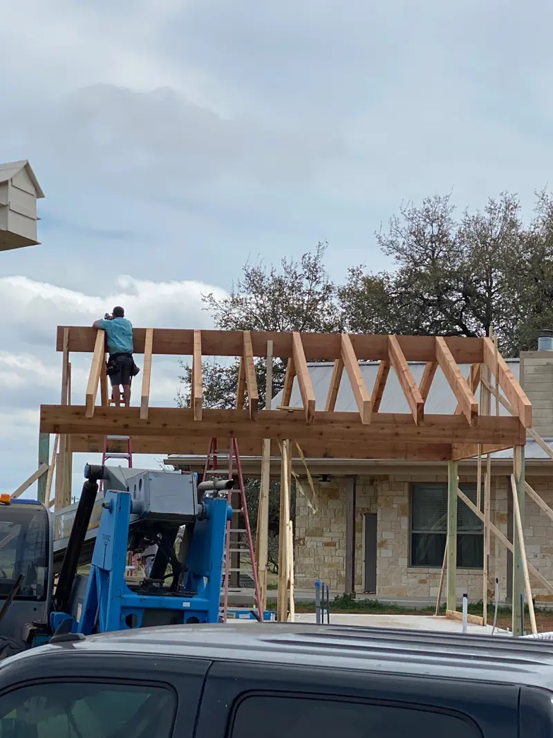 Crew setting cedar rafters on top of the frame, a truck in front.
