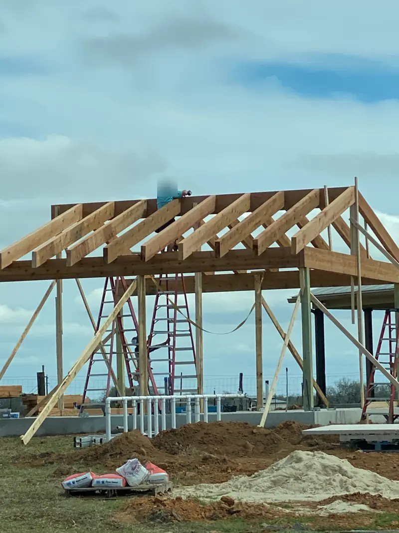 Rafters finished on the cedar frame, a sand pile beside the slab.