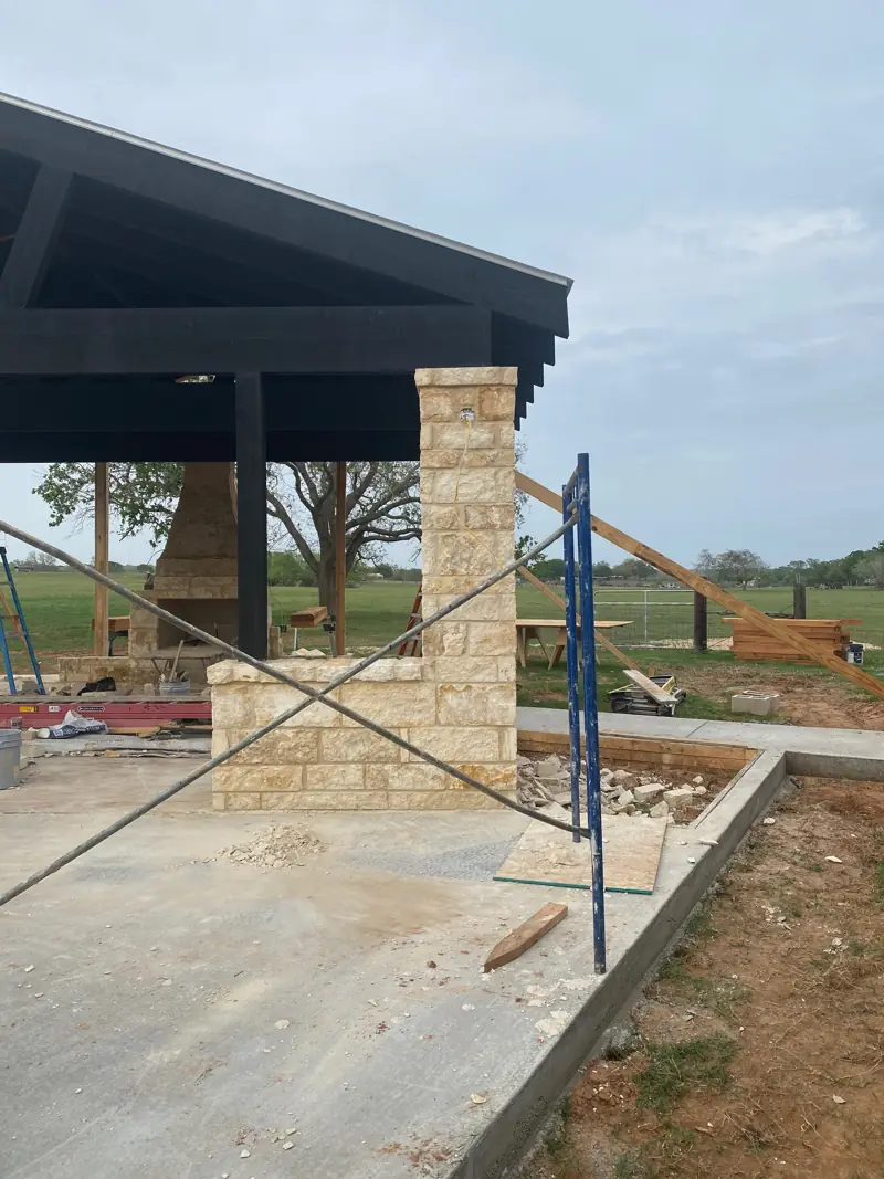 Stone column and low stone wall going up, scaffolding beside them.