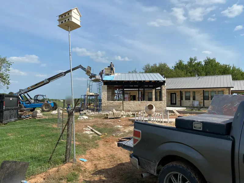 Telehandler lifting stone up to the chimney, a pickup in front.