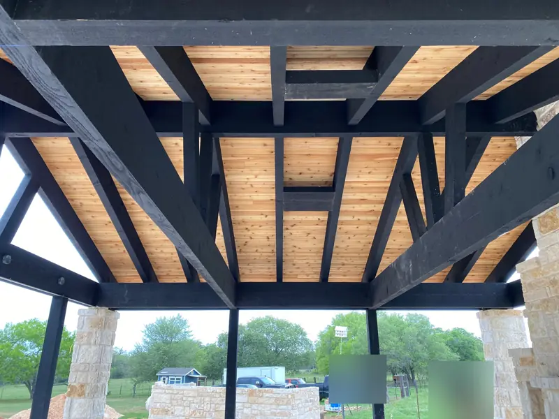 Black beams and cedar ceiling seen from below, stone columns at the corners.