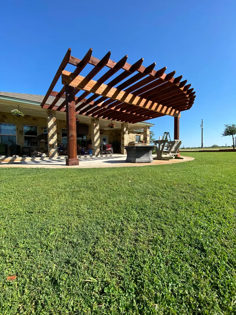 Curved cedar pergola over the patio, seen from the yard.