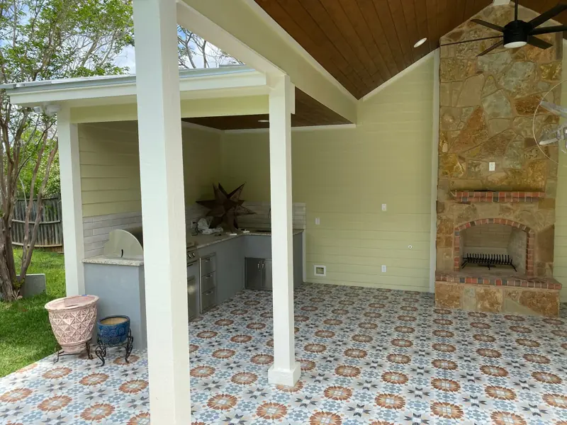 Outdoor kitchen with a grill beside the stone fireplace.