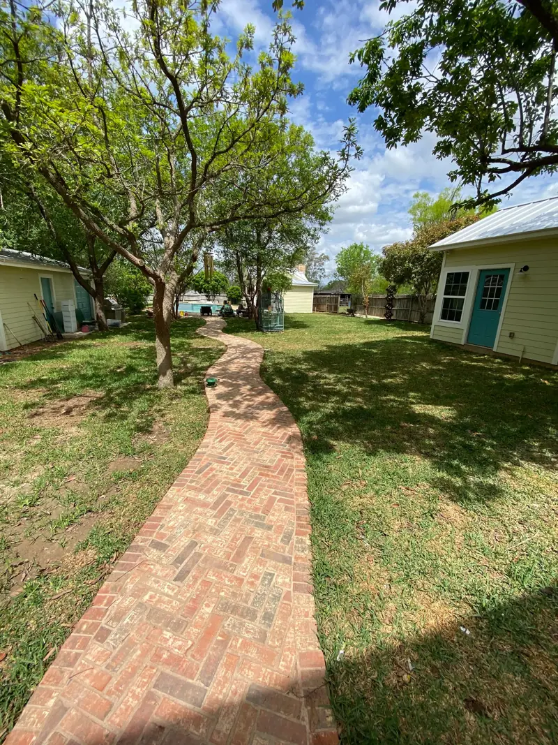 The brick walkway from the other end, the pool house at right.