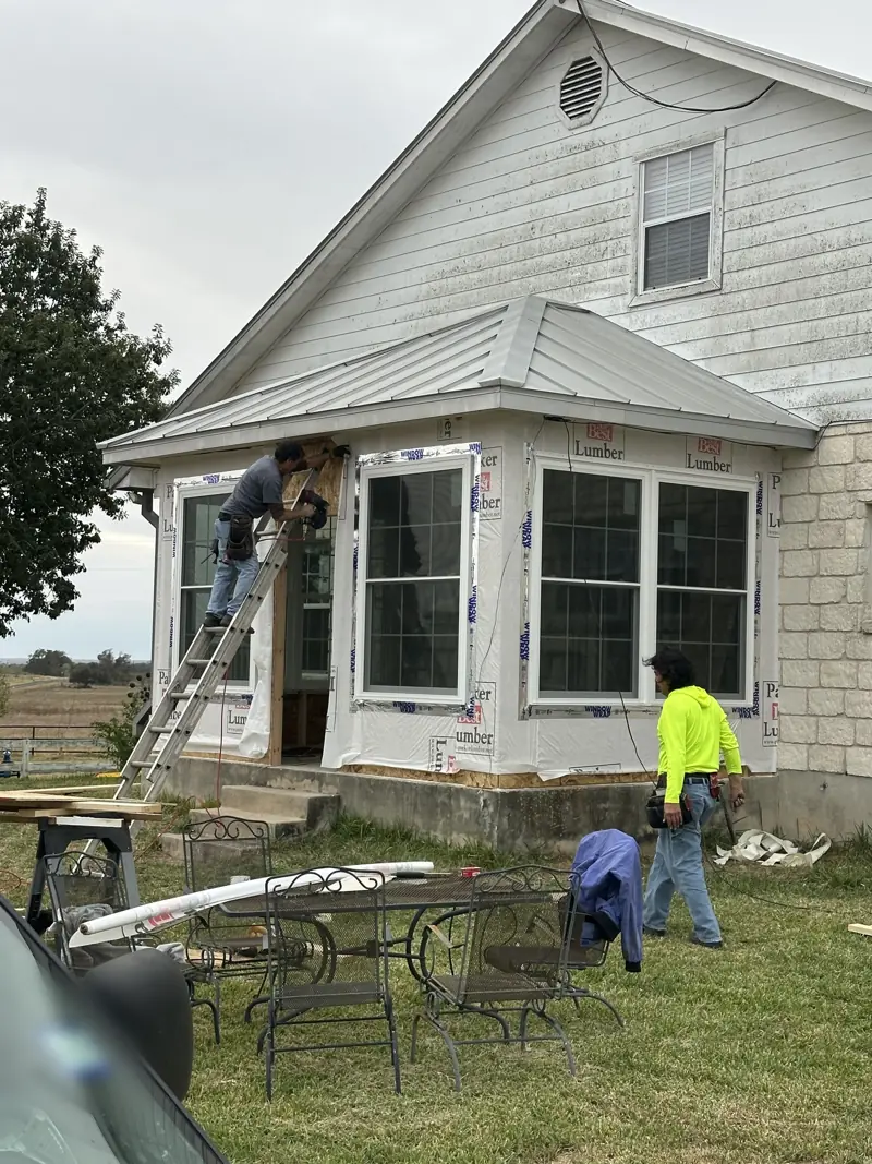 Covered porch being closed in with framed walls, new windows and house wrap.