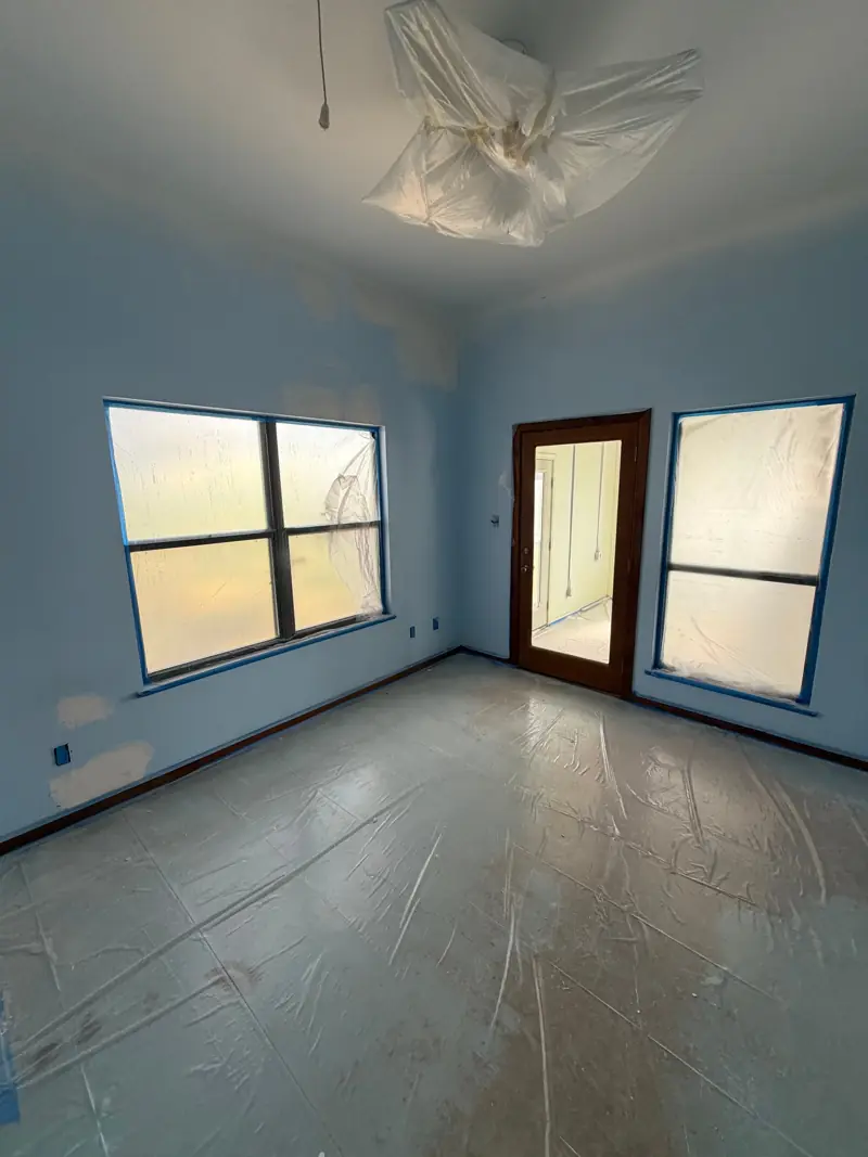 Bedroom with patched walls and plastic over the floor, ready for paint.