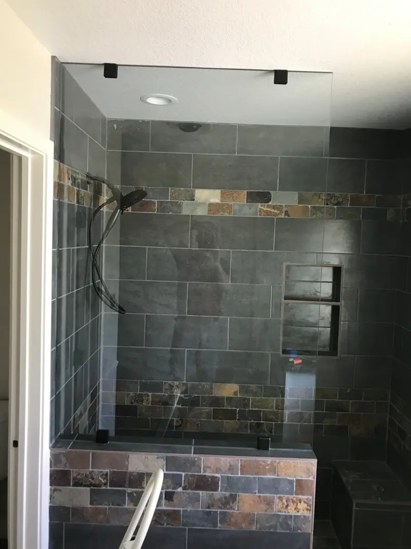 Slate tile walk-in shower with a glass panel, a niche and a tiled bench.