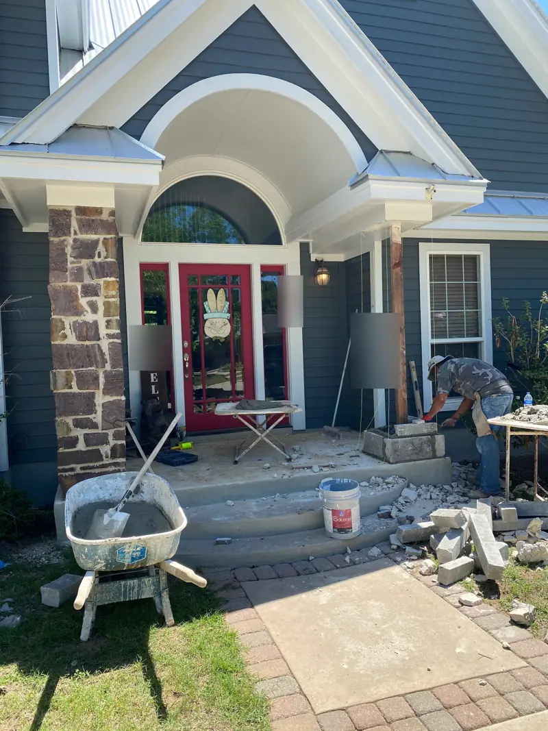 Front entry of a blue-gray house with the old stone coming off a porch column.