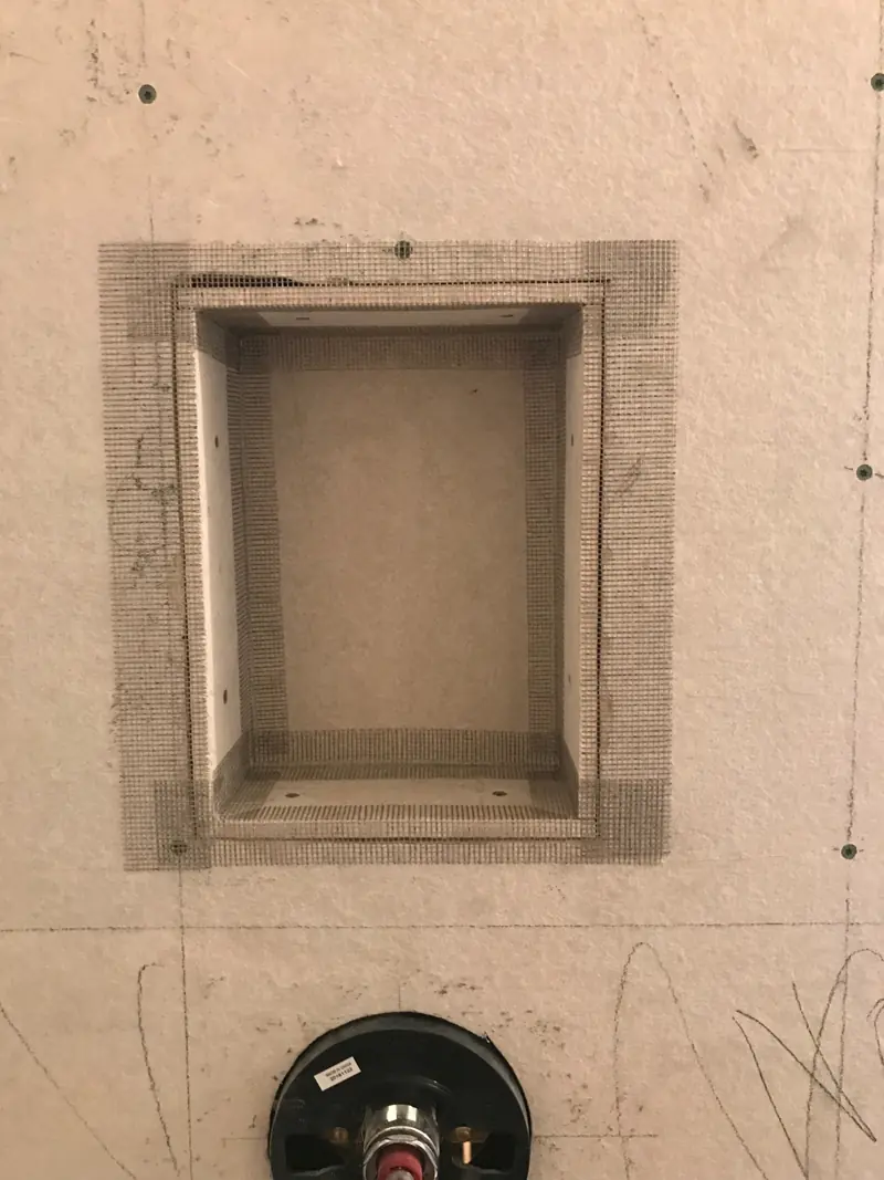 Close view of the shower niche taped into the backer board above the valve.