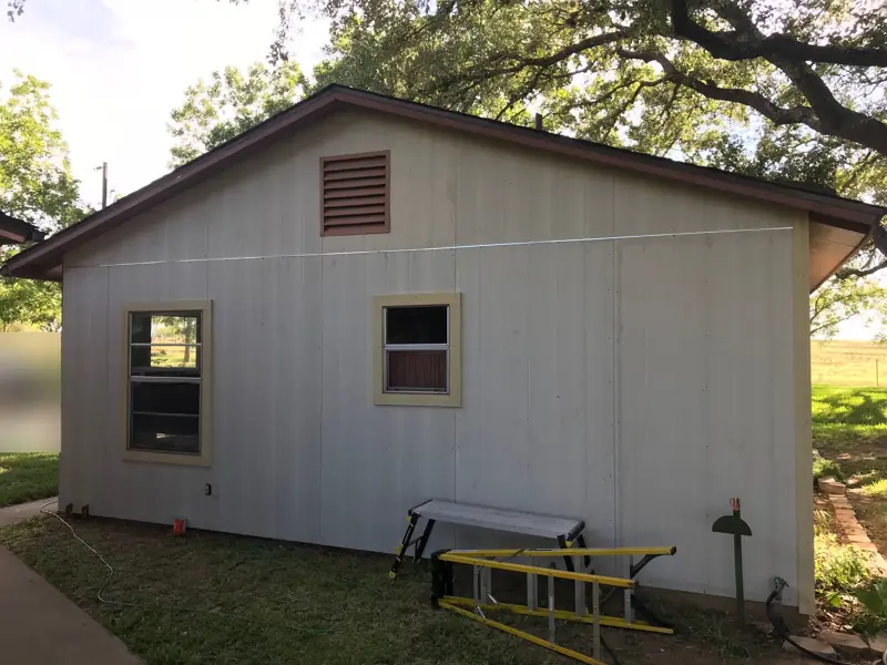 Gable end finished in pale vertical siding with a louvered vent near the peak.
